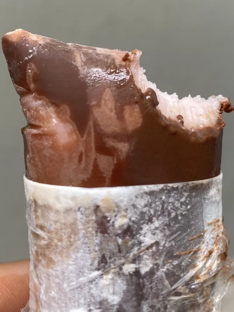 Geladinho de Morango Trufado mordido, com casquinha de chocolate e recheio de morango