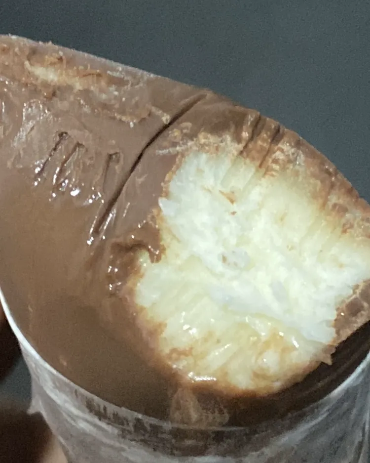 Geladinho de Ninho Trufado mordido: casquinha de chocolate e recheio cremoso de Ninho